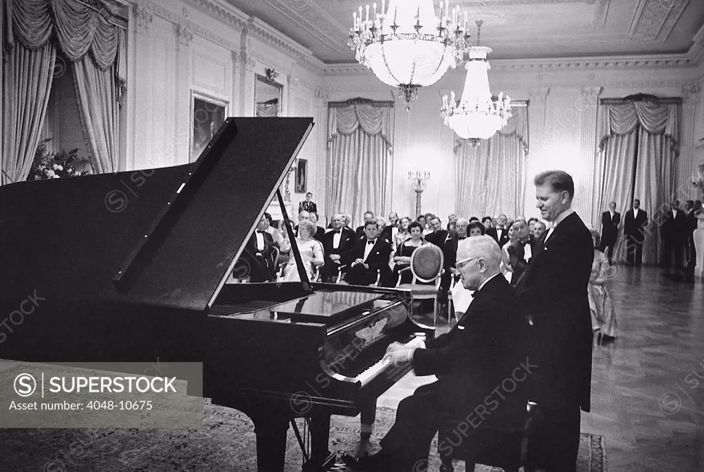 Former President Truman plays the White House piano in the East Room as master pianist Eugene List awaits his turn. In the audience front row are Bess Truman, President Kennedy, Mrs. Kennedy, and Vice President Johnson. Nov. 1, 1961.
