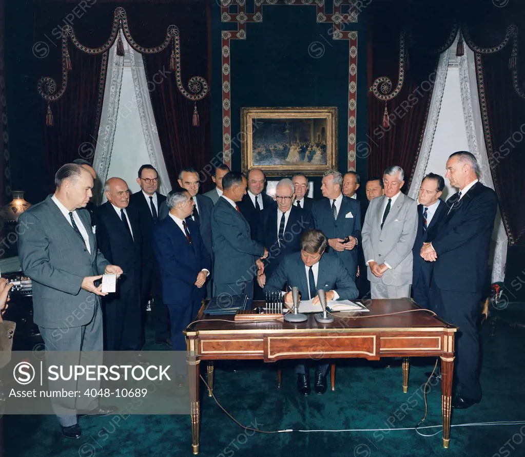 President Kennedy signing the Nuclear Test Ban Treaty which banned nuclear tests in the atmosphere, underwater and in space. First row: Senators Pastore, Fulbright, Aiken, Dirksen, Saltonstall, Kutchel, and VP Johnson. Second Row: Averell Harriman, Sen. Smathers, Sec of State Dean Rusk, Sen. Humphrey, William C. Foster, Sen. Cannon. Oct. 7, 1963.