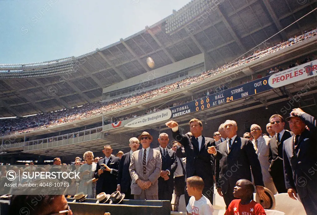 President Kennedy throws out first ball of the 32nd All-Star Baseball Game. Flanking the President, L-R: Speaker John McCormack, Dave Powers, VP Johnson, President Kennedy, Baseball Commissioner Ford Frick, Lawrence O'Brien. July 10, 1962.