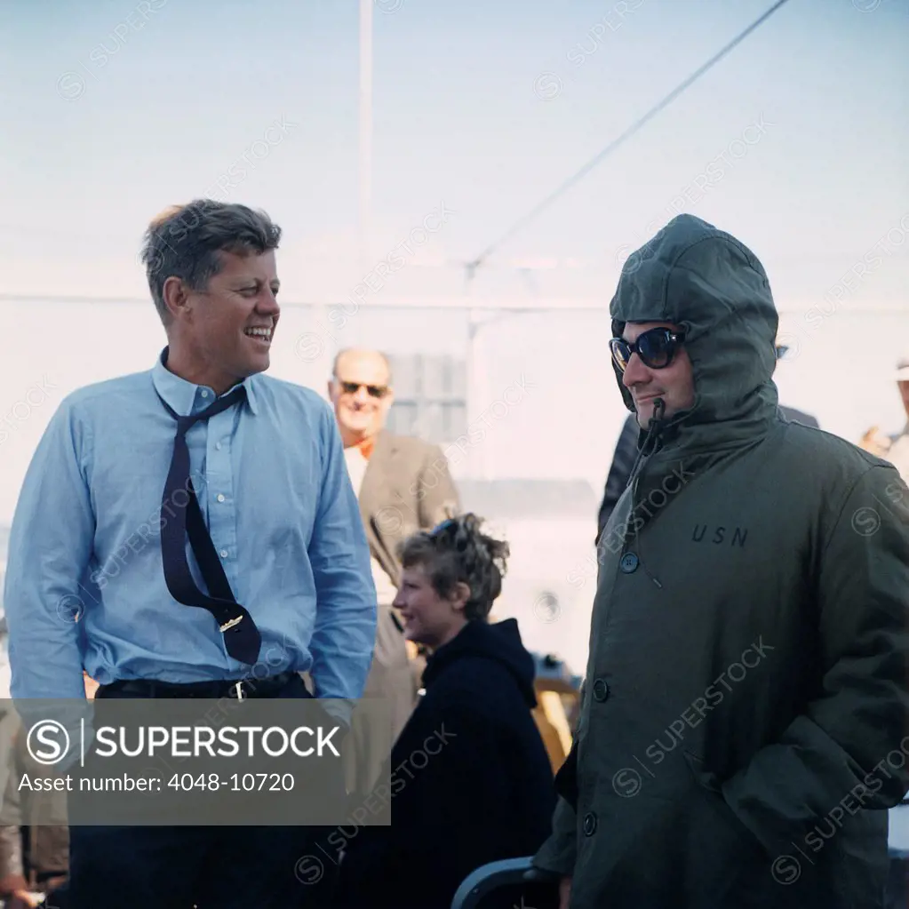 President Kennedy stands beside his bundled up Press Secretary, Pierre Salinger. They are watching the America's Cup Race from the Deck of the USS Joseph P. Kennedy, Jr. off Newport, Rhode Island, on Sept. 15, 1962.