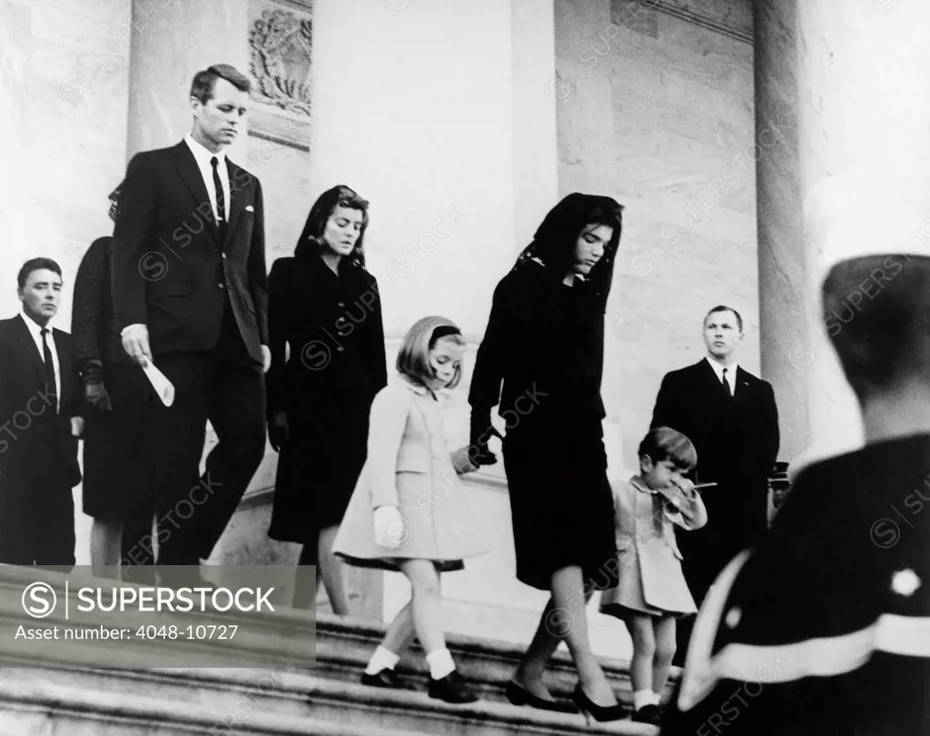 President Kennedy's family leaves the Capitol after a funeral ceremony. Caroline Kennedy, Jacqueline Kennedy, John F. Kennedy, Jr., followed by Robert Kennedy, Jean Kennedy Smith and Peter Lawford. United States Capitol, East Front, Washington, D.C. Nov. 24, 1963.