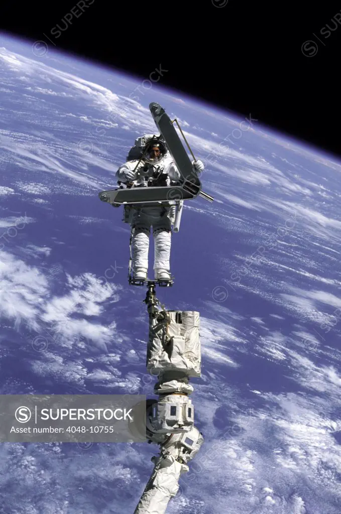 Construction work on International Space Station. Astronaut Lee Morin totes a large, but weightless, metal piece just removed from the space station exterior. No longer needed, it will be attached to the station exterior for long term storage. April 13, 2002.
