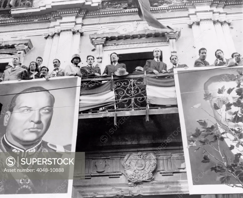 Bolivian political celebration. The Bolivian cabinet awaits the arrival of President Victor Paz Estenssoro. The balcony is decorated with giant photos of former president Gualberto Villarroel López (left) and Paz Estenssoro. 1952.