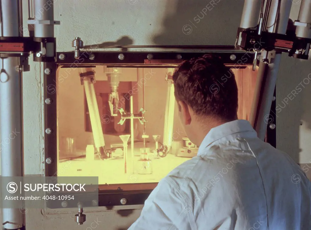 Nuclear engineer is protected from radiation by a fifty-two inch thick, oil-filled glass window as he examines irradiated materials. NASA's Plum Brook Station in Sandusky, Ohio, 1961.