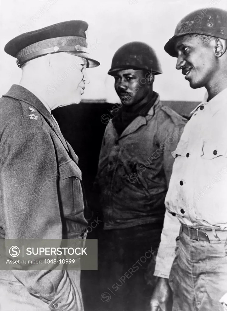 General Dwight Eisenhower talking with two African American soldiers at the supply port of Cherbourg, France. Eisenhower commanded a segregated US military during World War II.