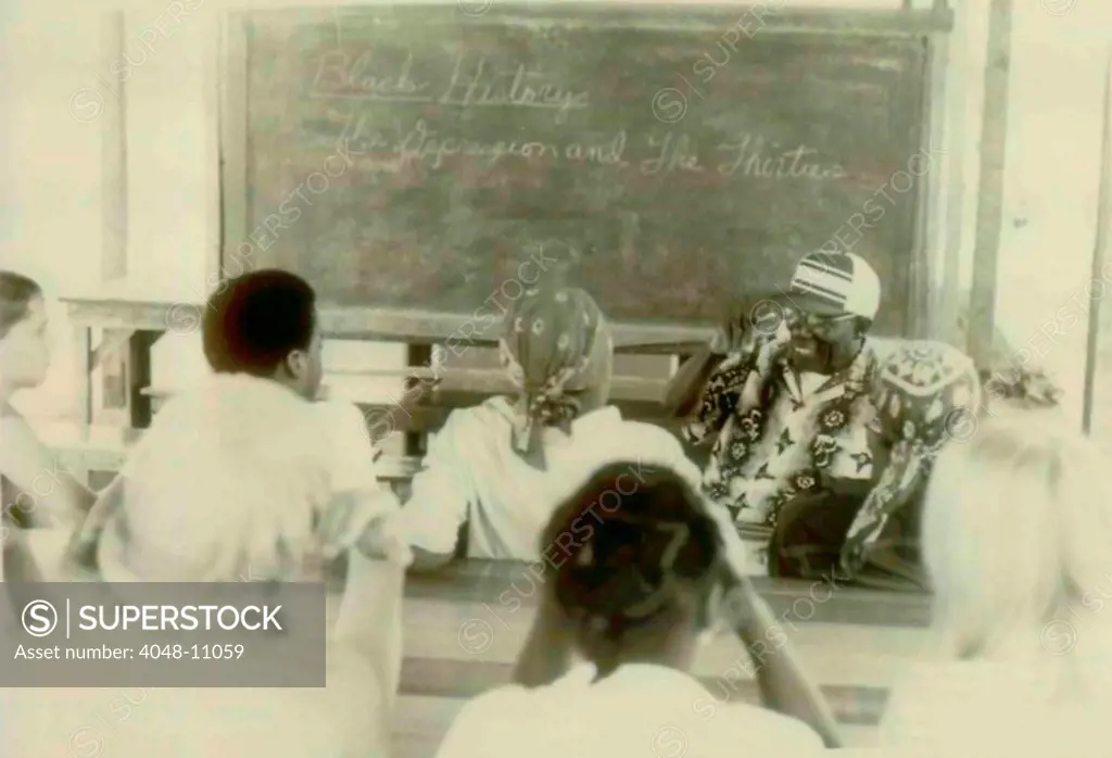 Henry Mercer teaching school. Written on the blackboard is 'Black History. The Depression and the Thirties.' The People's Temple Agricultural Project. Jonestown, Guyana. Nov. 1978.