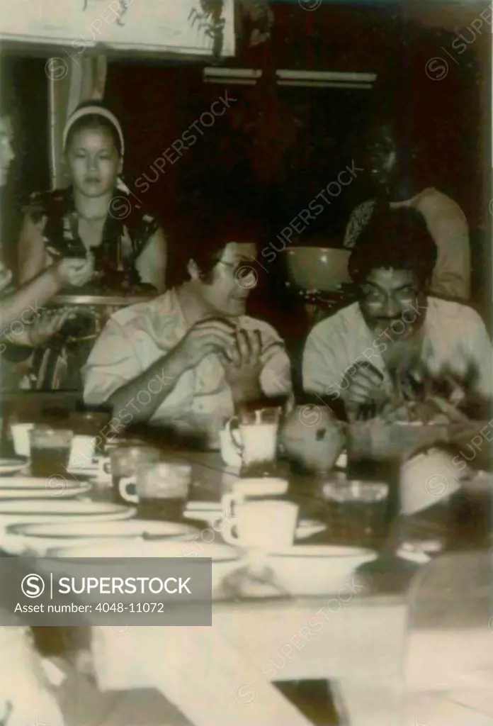 Jim Jones and a guest in Jonestown. At left is Kim Tschetter serving dinner. People's Temple Agricultural Project. Jonestown, Guyana. Nov. 1978.
