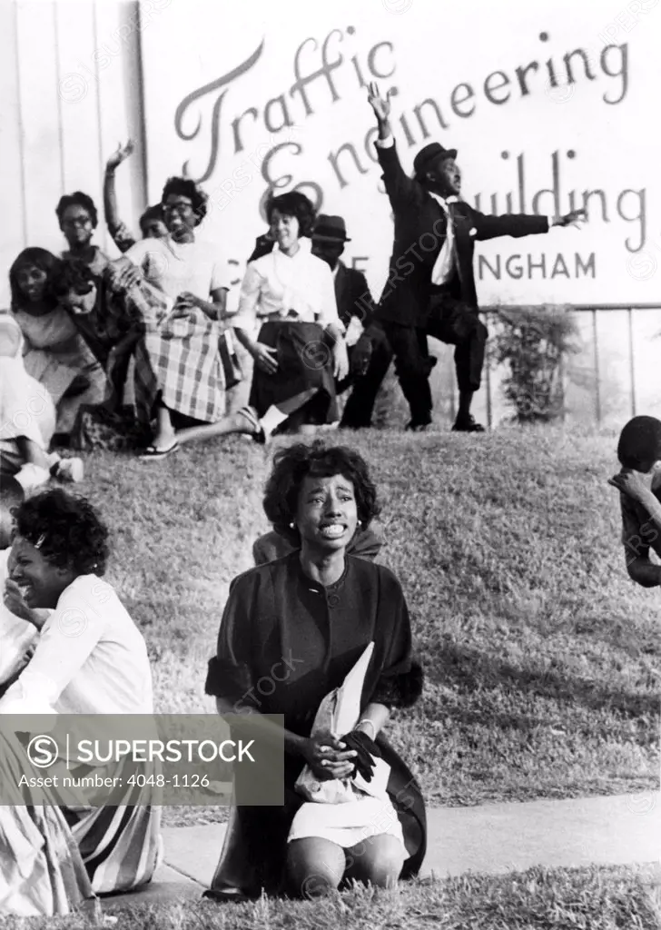 Birmingham, Alabama: A young woman kneels in prayer on sidewalk outside city traffic engineering building, 5/5/63, during anti-segregation protest deomonstration. Hundreds of African-American children and adults were arrested at this deomstration.