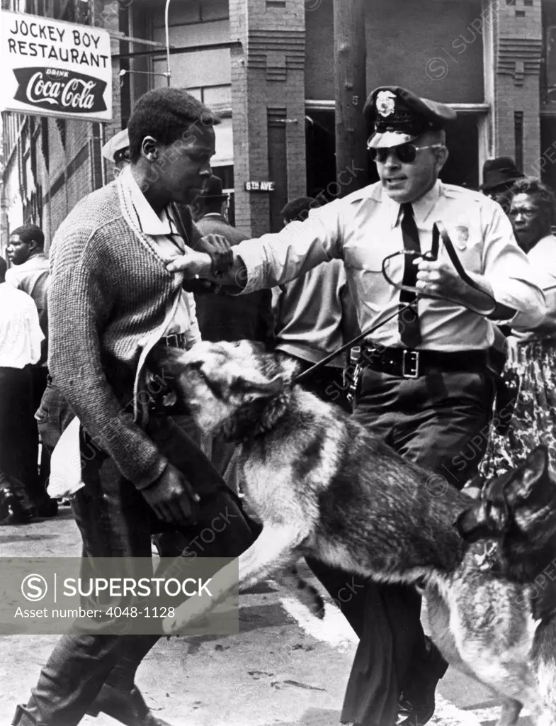 A Black man is attacked by a policeman and dog, 1963.