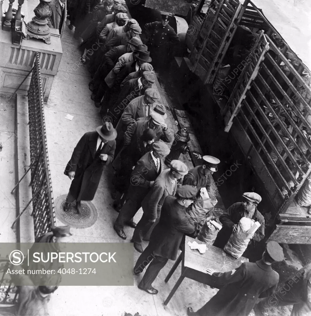 Food handouts in New York in 1930. Police stations were used as distribution centers. Photo shows food being distributed in front of the East 104th Stree station house.