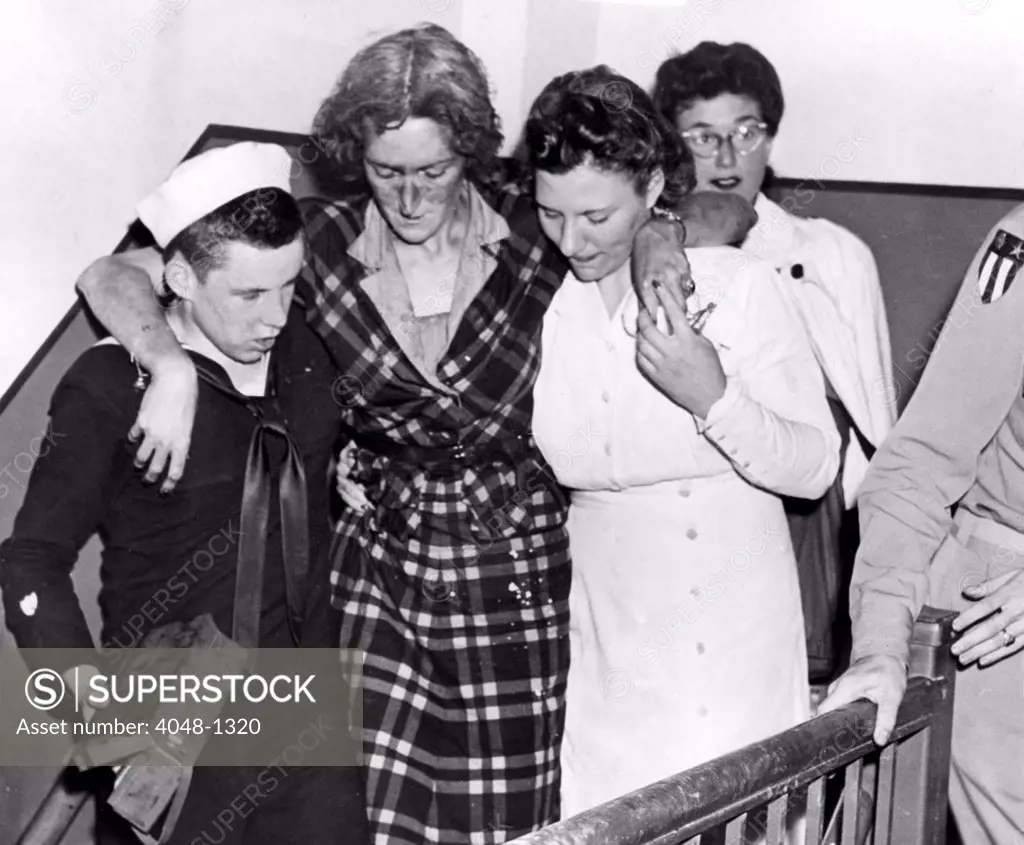 HERO OF EMPIRE STATE BUILDING DISASTER NEW YORK--First aid kit in one hand, Don Molony, 17-year-old Coast Guardsman, helps an unjured woman down stairs in the stricken Empire State Building on the morning of July 28. 7/28/45.