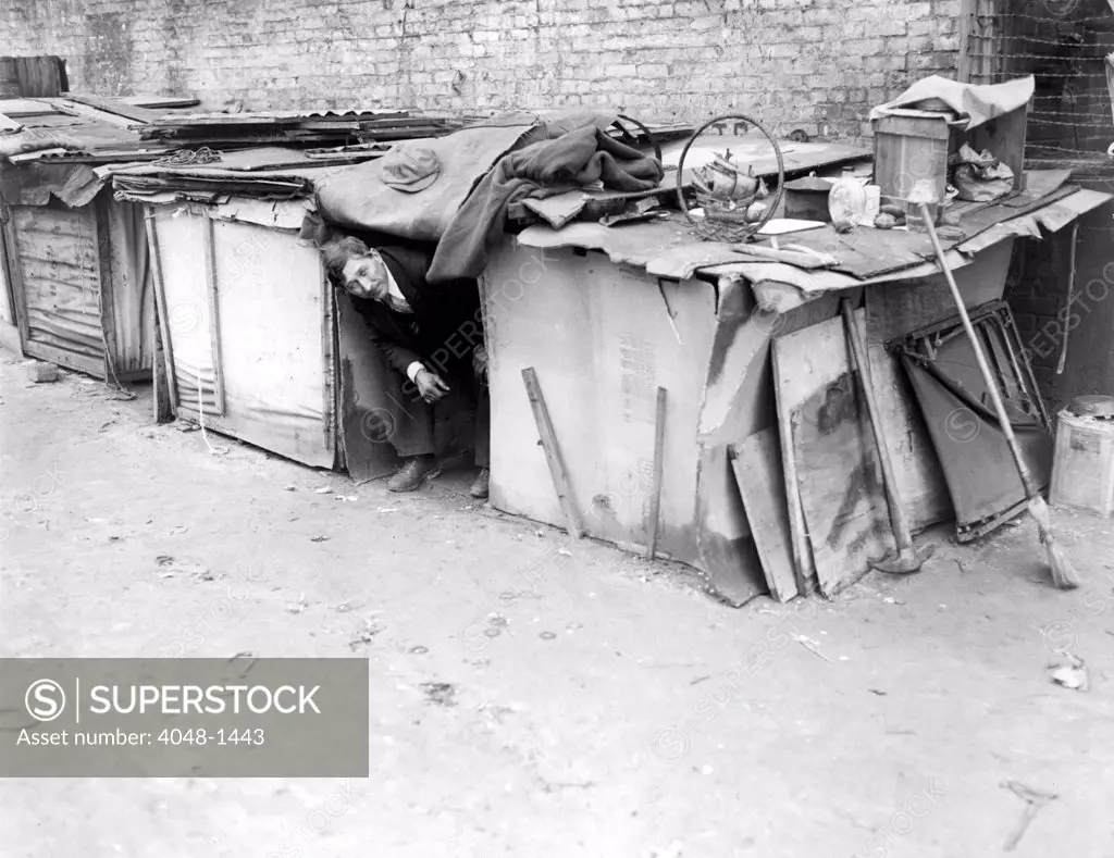 An unemployed man living in a shack constructed from packing cases and pieces of wood in New York City, off Broadway on West Houston Street.  February 8, 1933.