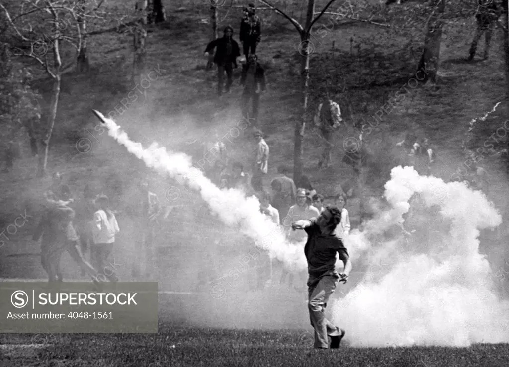 KENT STATE UNIVERSITY, student tosses a tear-gas bomb back at the National Guard who fired it to disperse the crowd  Kent, Ohion 5/4/70
