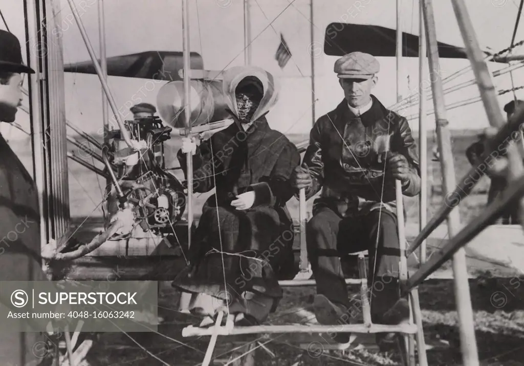 Katharine Wright sits beside brother Wilber at the beginning of her first ride in an airplane. Photo was taken in southern France on Feb. 15, 1909. Note that her coat and skirt are tied down  (BSLOC_2018_2_152)