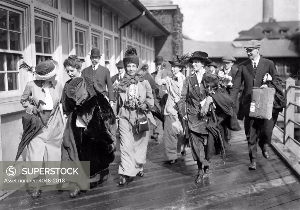 Mrs. Emmeline Pankhurst, the English militant leader (center), is shown leaving Ellis Island today with party of suffragists after President Wilson had ordered her release.  October 20, 1913.