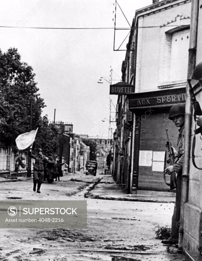 FRANCE--Defenders of a pillbox guarding a street in Cherbourg, German soldiers surrender, waving a white flag, after being knocked out of their position by allied tank fire. Soldiers in doorway of building at right keep guns on the ready on the lookout for any escape moves. Nazis carry their own wounded as they move defectedly in defeat with their