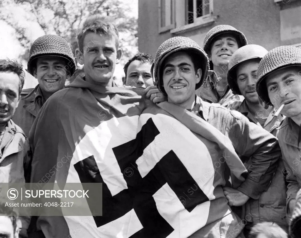 CHERBOURG, FRANCE-- A comandeered Nazi flag held by American soldiers after the liberation of Cherbourg, July 1, 1944
