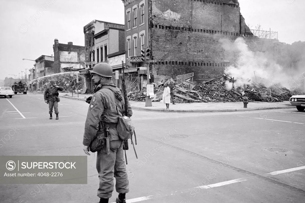 D.C. Riot, April '68. aftermath, soldier standing guard in a Washington D.C. street with the ruins of buildings that were destroyed during the riots that followed the assassination of Martin Luther King Jr., by Warren K. Leffler, April 8, 1968.