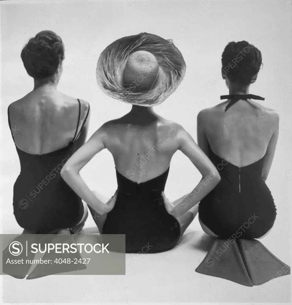 Back view of fashion models in swim suits, two kneeling wearing swim fins, and one seated, photograph by Toni Frissell, circa 1950.