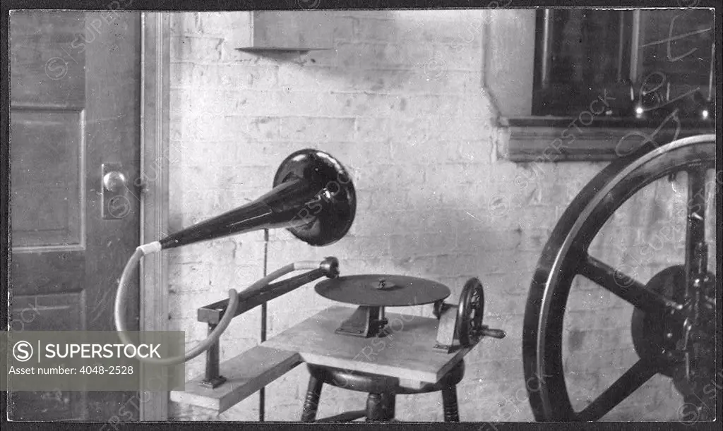 One of the first gramophones set next to a large mechanical wheel, by Emile Berliner, 1888.
