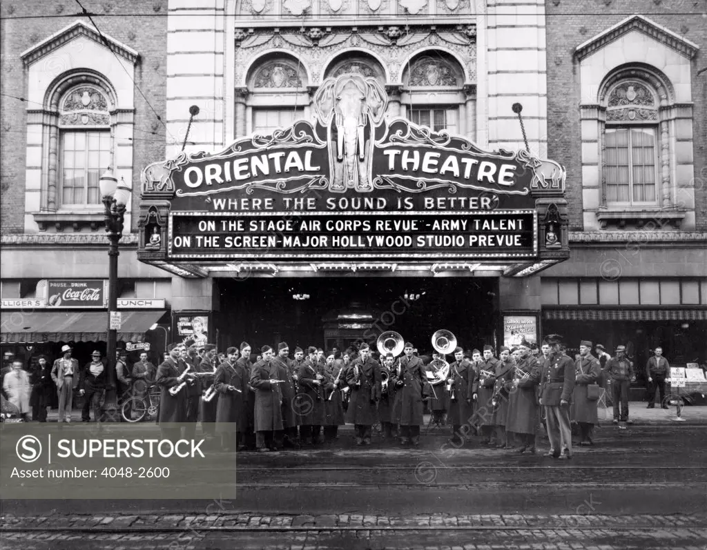 The Oriental Theatre exterior with brass band, marquee reads: 'Where the Sound is Better, on the stage Air Corps Review - Army Talent On the Screen-Major Hollywood Studio Preview', Eugene, Oregon, 1930.