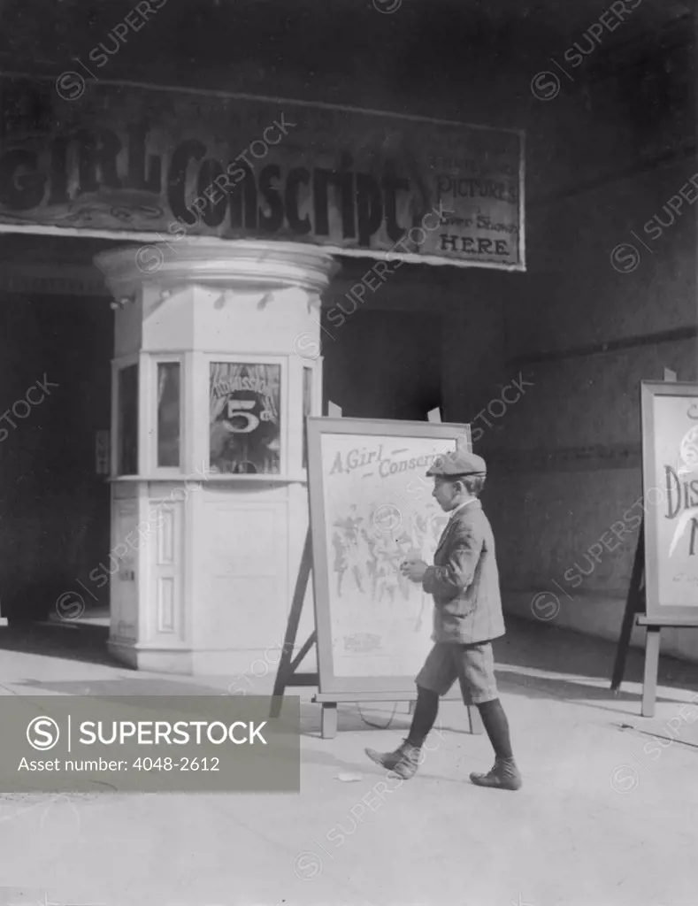 Boy in front of a movie theater showing THE GIRL CONSCRIPT, original caption reads: 'Where some of the newsboy's money goes', Wilmington, Delaware, photograph by Lewis Wickes Hine, May, 1910.