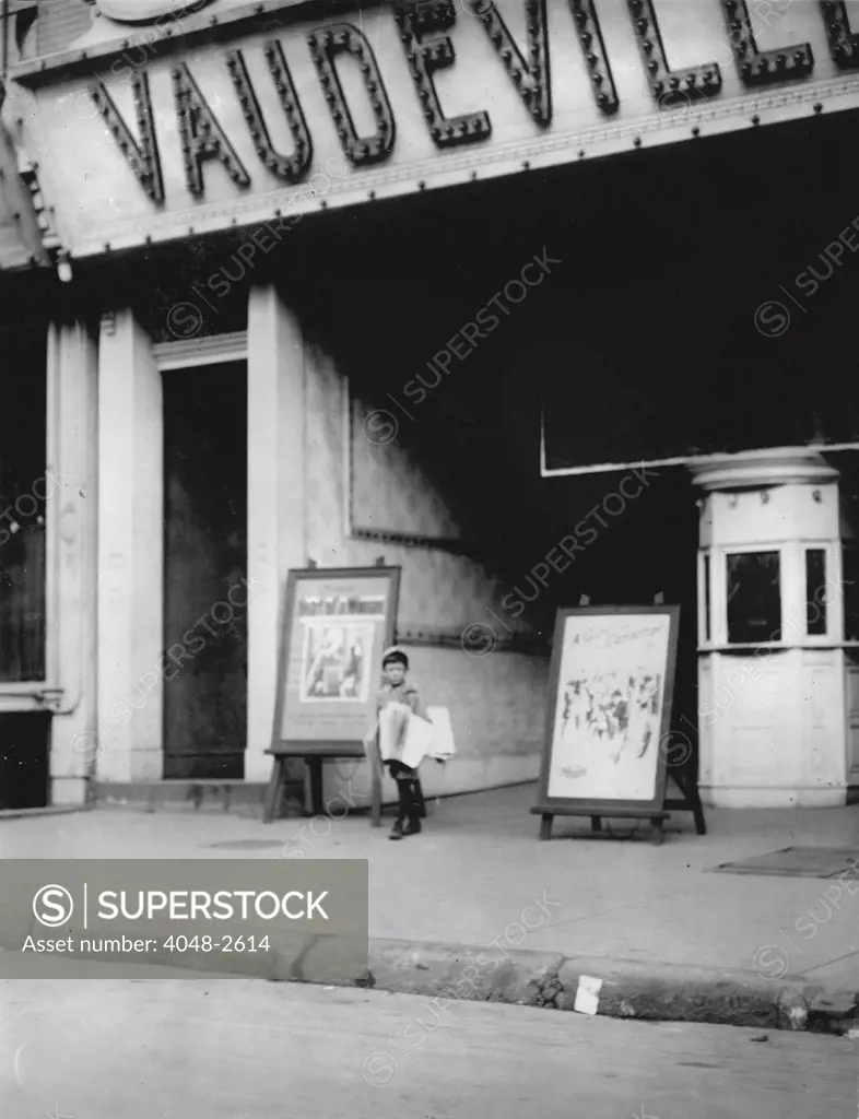 Child labor in front of a movie theater. Harry Silverstein, newsboy, 7 years old, sells papers 8 hours a day at 25 cents per week, doesn't smoke, visits saloons, Wilmington, Delaware, photograph by Lewis Wickes Hine, May, 1910.