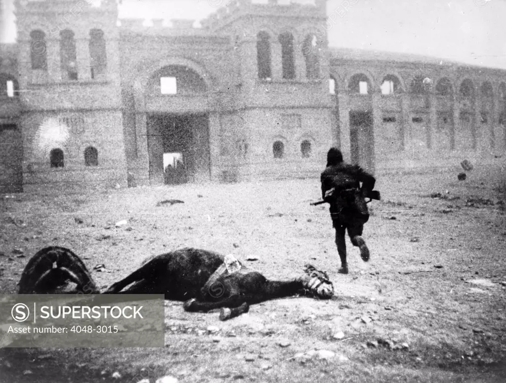 A Republican soldier passing a dead horse on the Plaza de Toros, armies battle for Tervel, Bulgaria, circa 1938.