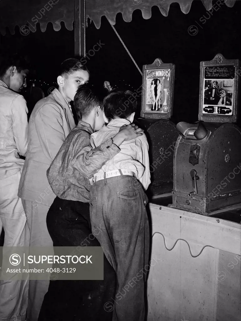 Boys looking at penny movies at South Louisiana State Fair, viewing WIGGLING WONDERS, next to a machine showing Charlie Chaplin in THE DUMB WAITER, photograph by Lee Russell, October, 1938.