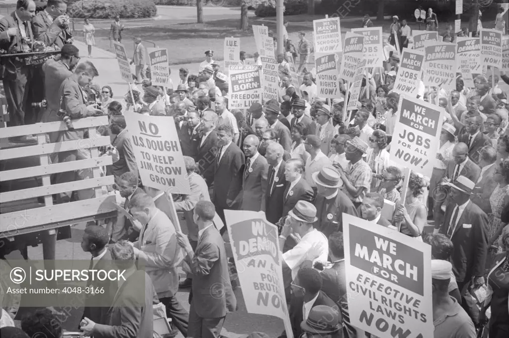 Civil rights march on Washington DC, photograph shows civil rights leaders, including Martin Luther King Jr. (center left, to right of sign reading 'No U.S. dough to help Jim Crow Grow'), surrounded by crowds carrying signs, photograph by Warren K. Leffler, August 28, 1963.