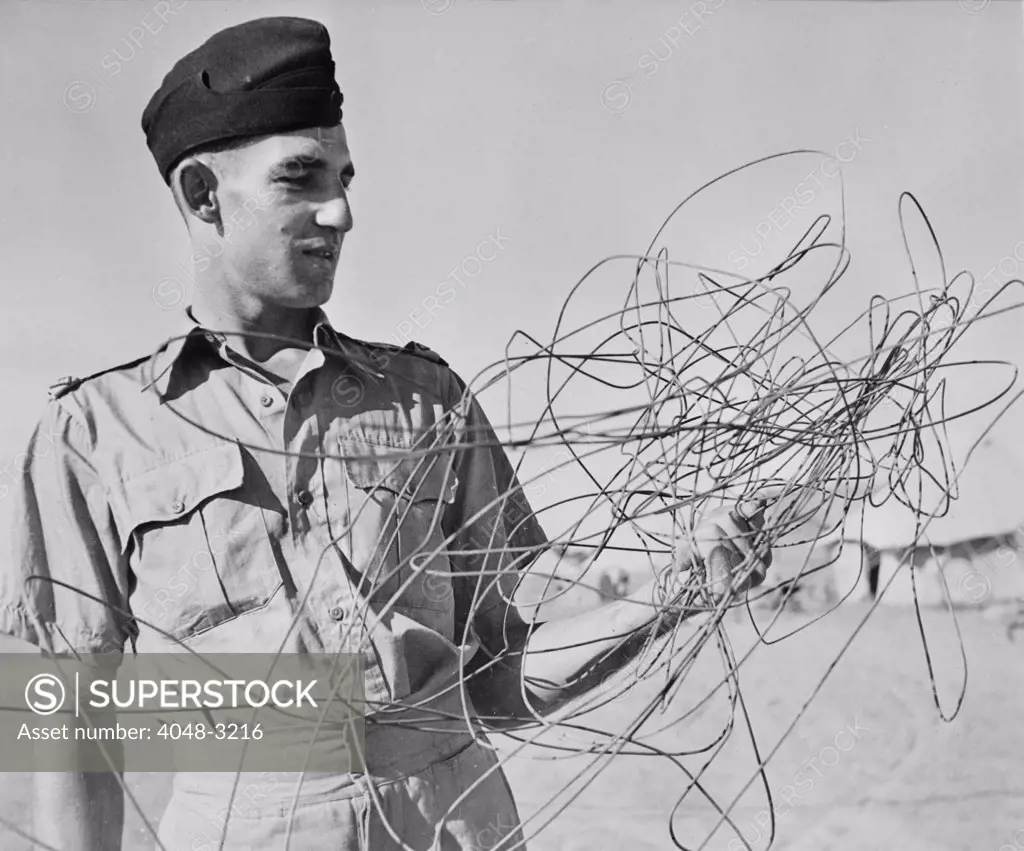 World War II, Sergeant C.M. Battleship, of Sydney, Australia, Leader of a Royal Air Force attack, examining telephone wire draped from his plane when he returned to base, circa 1942.