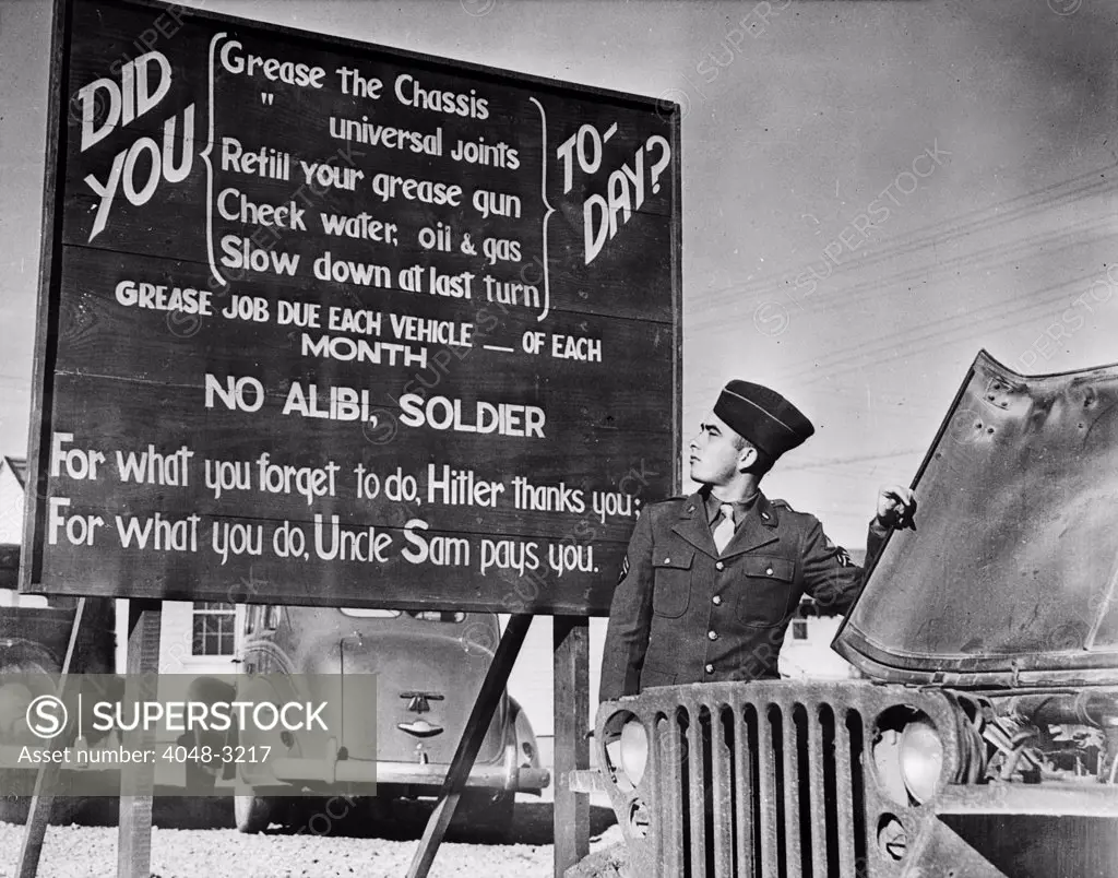 World War II, U.S. soldier  at base in front of patriotic message, circa 1940-1946.