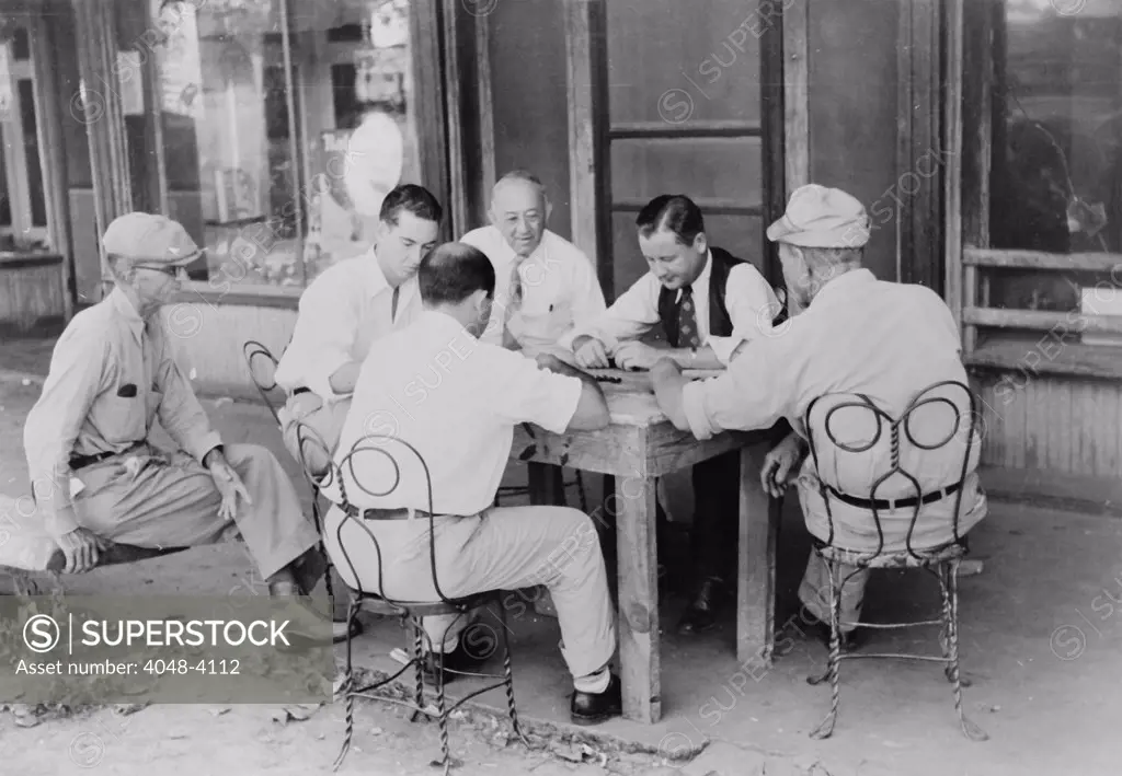 Playing dominoes or cards in front of drug store in center of town in Mississippi Delta, Mississippi, photograph by Marion Post Wolcott, 1939