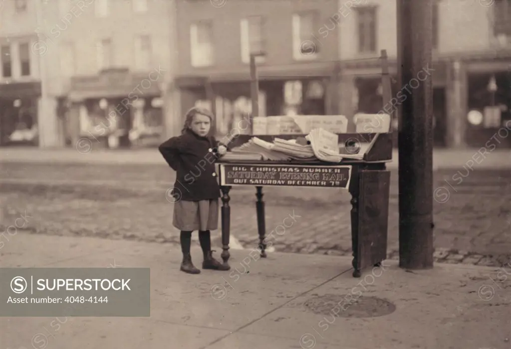 Child labor, Little girl, apparently 6 years old, but didn't know her name or age, tending stand at Washington and 3rd Street, for older sister, saloon on corner, Hoboken, New Jersey, photograph by Lewis Wickes Hine, December, 1912.