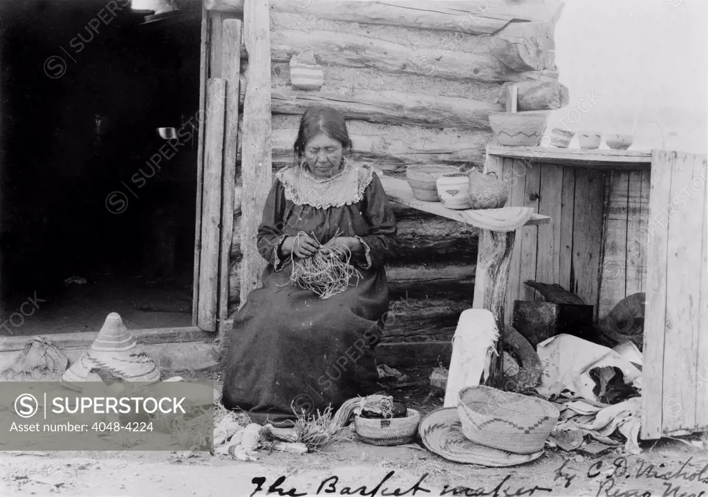 American Indian woman making a basket, original title: 'The basket maker' Reno, Nevada, photograph by C.D. Nichols, November 2, 1904