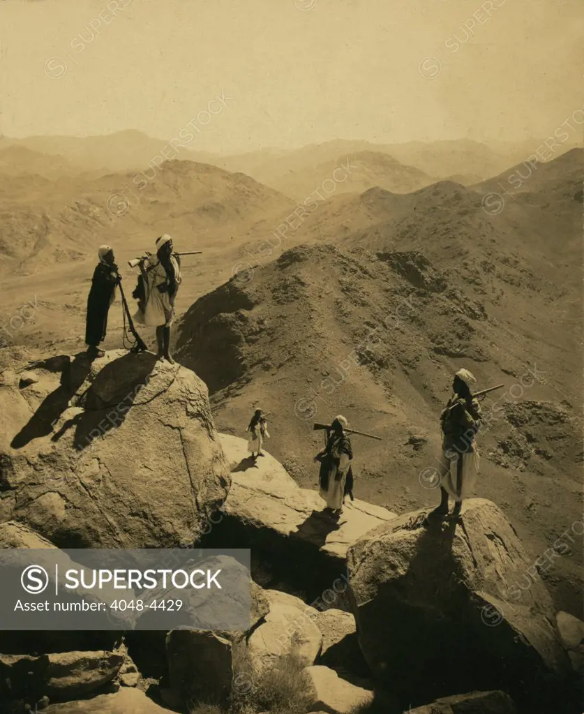 Mount Sinai, men with rifles standing on boulders looking out over valley and mountains, south by West, from the summit of Mount Catherine, 8536 feet the highest in Mount Sinai desert, photograph by Underwood & Underwood, April 15, 1913