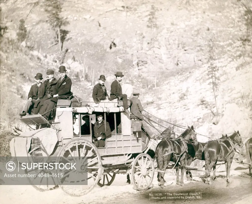 The Deadwood Coach. Side view of a stagecoach; formally dressed men sitting in and on top of coach. Deadwood, SD. John C. Grabill, 1889