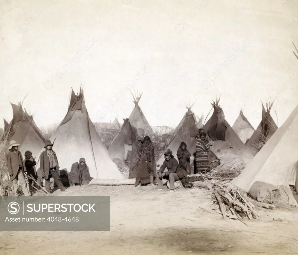 What's left of Big Foot's band. Miniconjou (children and adults)--many are looking away from camera--in a tepee camp, probably on or near Pine Ridge Reservation. Pine Ridge, South Dakota.  Photo by John C. Grabill. 1891