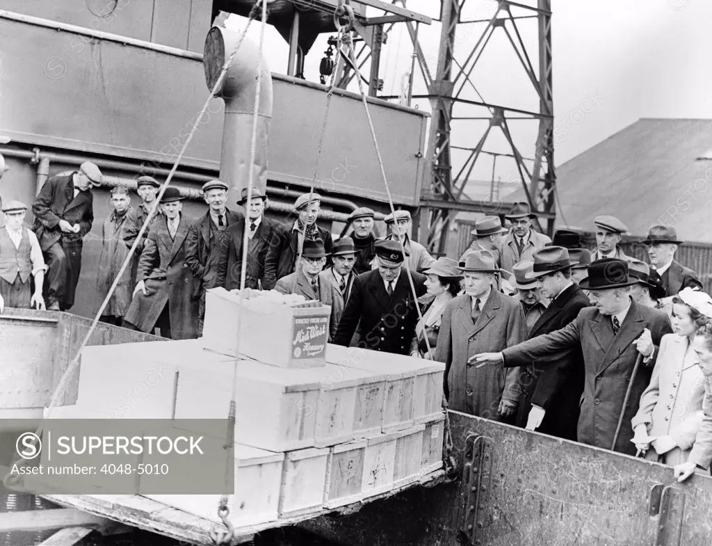 World War II. Meeting the first lend-lease consignment of American food being lifted from the hold of the ship at a British port. Right to Left: Kathleen Harriman, Lord Woolton, Minister of Food; Averill Harriman, U.S. lend lease representative; Robert H. Hinkley, U.S. Assistant Secretary of Commerce. ca. 1941