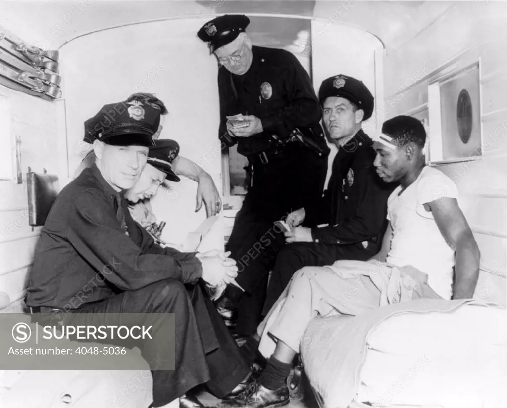 Policemen and wounded African American man inside police ambulance, during the 'Zoot Suit' riot of 1943.  Ethnic based hostility, provoked by the urban hipster 'Zoot Suit' fashion, resulted in violent attacks on civilian youths by mobs of service men. Los Angeles, June, 1943
