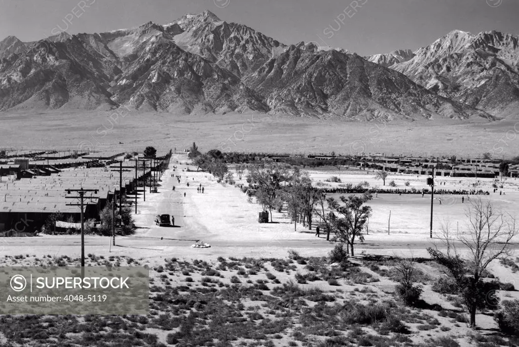 World War II, Bird's-eye view of Manzanar Relocation Center, showing buildings, roads, and Sierra Nevada mountains in background.  California. photograph by Ansel Adams. 1943