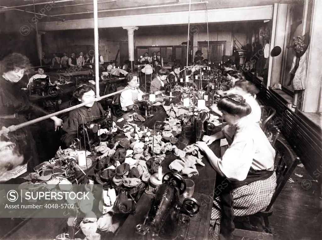 Women workers sewing teddy bears in an sweat shop assembly line. Women are engaged at the sewing machines, while men associated with the operation are in the background. New York City, 1915
