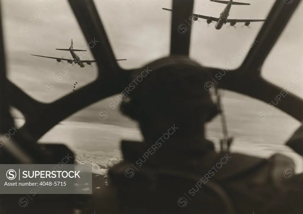 Two B-29 Super-fortresses drop bombs over Malaya as seen from the cockpit of a third bomber during a run over the important railway yards and repair shops utilized by the Japanese at Kuala Lumpur. 1943-45.