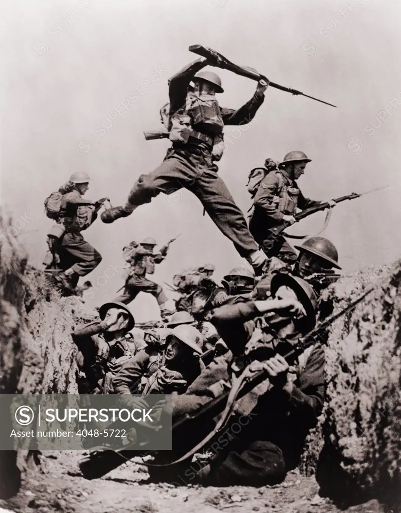 British Black Watch regiment in training in 1940. Members of the regiment crouch in a trench while others jump across overhead during a bayonet charge.