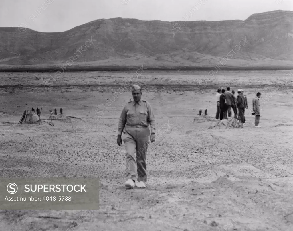 General Leslie Groves (1896-1970), walking across the site of the first atomic bomb blast site at Alamogordo, N.M. in July 1945. Groves was the military leader of the Manhattan Project to develop the Atomic Bomb. He was played by Paul Newman in the 1989 movie, FAT MAN AND LITTLE BOY.