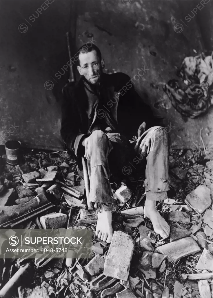 French prisoner at Nordhausen Concentration camp amid prison rubble waiting for an ambulance to take him to a hospital after liberation by First U.S. Army on April 11, 1945.