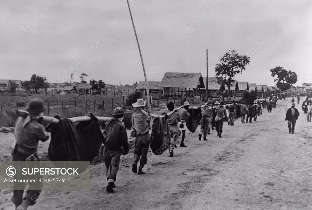 Near end of the Bataan Death March, US prisoners of war carry dead comrades in improvised stretchers of bamboo poles and blankets. 90,000 Filipino and American prisoners of war troops were marched 60 miles under brutal conditions, resulting in the death of an estimated 7,000-10,000 men.