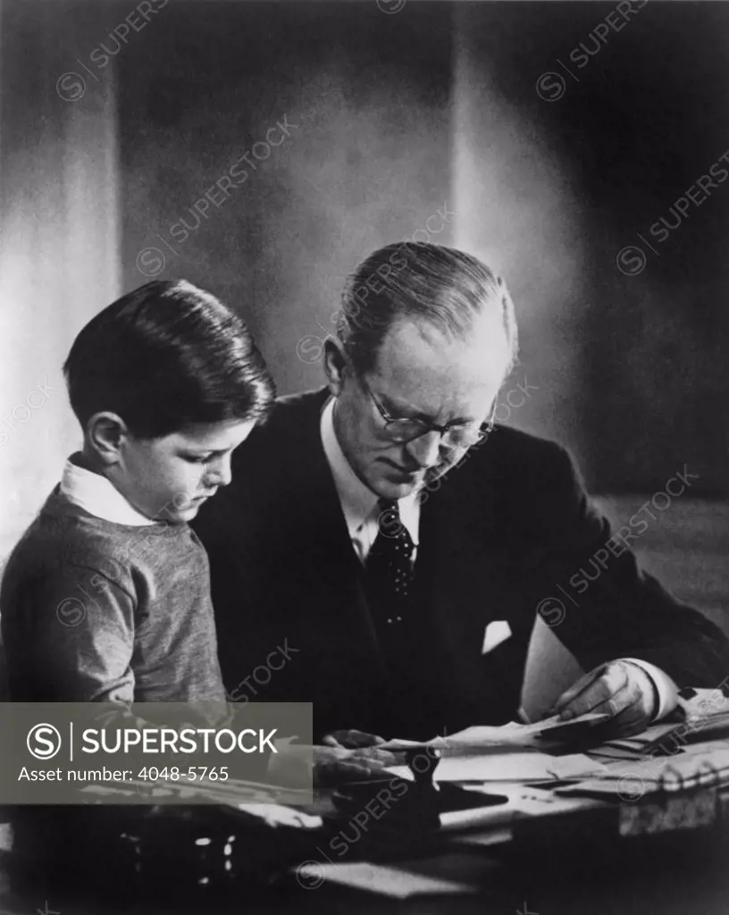 Ambassador to Great Britain, Joseph Kennedy, in his London study, helping his youngest son, Edward Kennedy, with his studies. Ca. 1938.