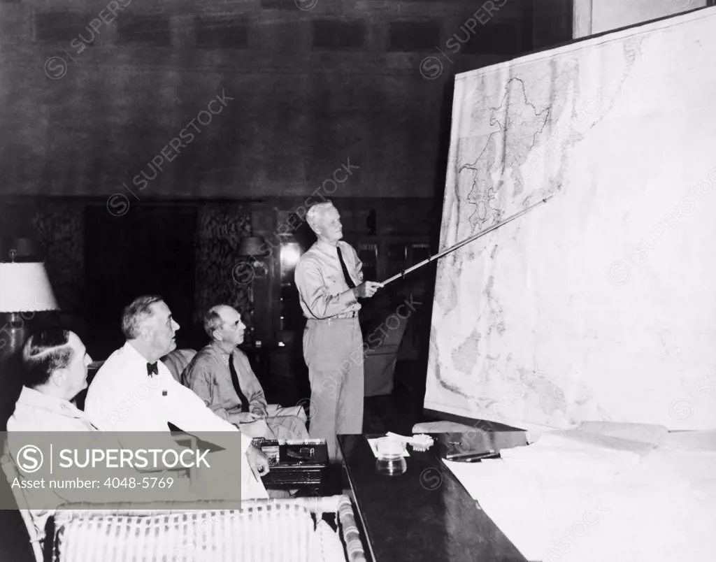 President Roosevelt meeting with General Douglas MacArthur, Admiral William D. Leahy, and Admiral Chester W. Nimitz, who is pointing to Tokyo on a large map. August 1944.