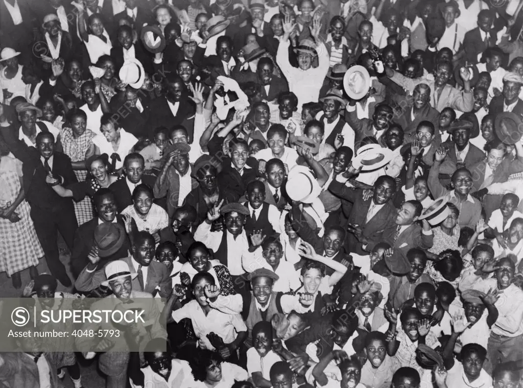 Harlem crowd celebrating African American boxer, Joe Louis' victory against former heavyweight champion, Primo Carnera. June 19, 1935.
